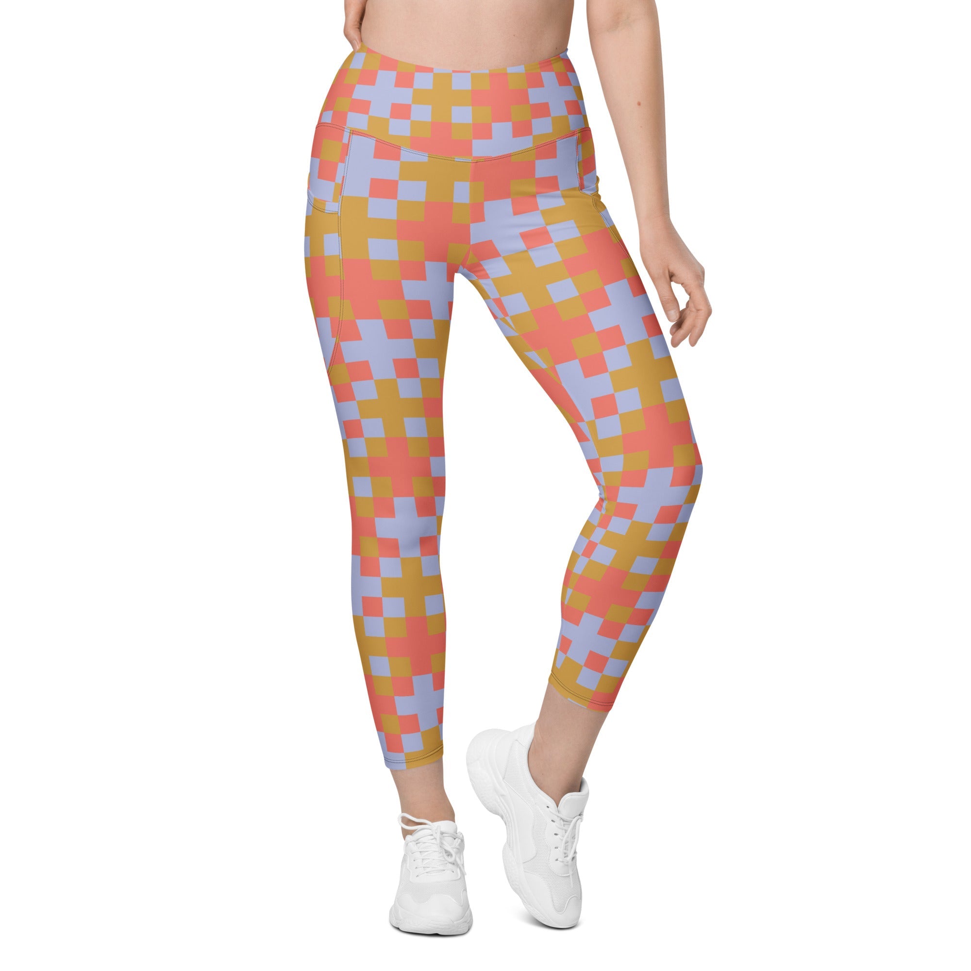A model wearing the high-waisted Pixel Glam Sculpt Leggings, highlighting the colorful terracotta, gold, and blue pixelated grid pattern and the integrated side pocket design.