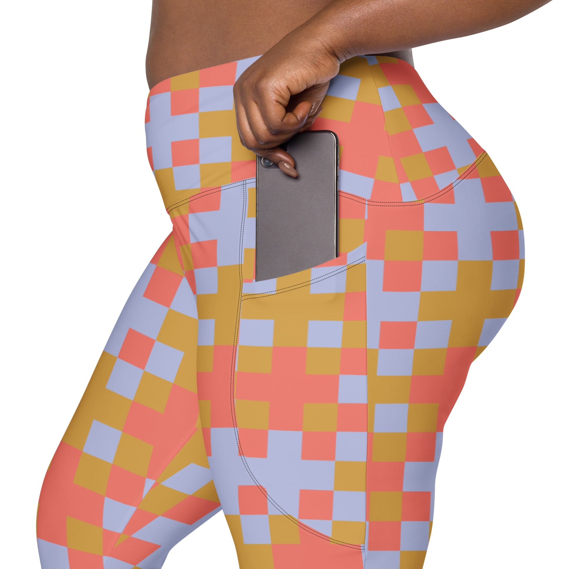 A model wearing the high-waisted Pixel Glam Sculpt Leggings, highlighting the colorful terracotta, gold, and blue pixelated grid pattern and the integrated side pocket design.
