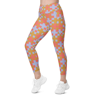 A model wearing the high-waisted Pixel Glam Sculpt Leggings, highlighting the colorful terracotta, gold, and blue pixelated grid pattern and the integrated side pocket design.