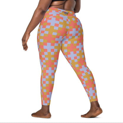 A model wearing the high-waisted Pixel Glam Sculpt Leggings, highlighting the colorful terracotta, gold, and blue pixelated grid pattern and the integrated side pocket design.