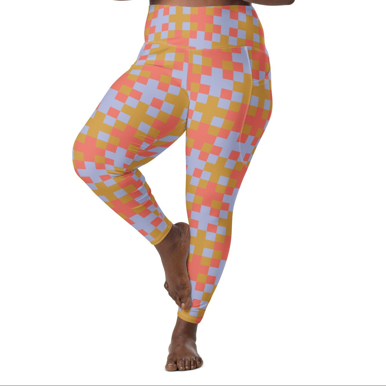 A model wearing the high-waisted Pixel Glam Sculpt Leggings, highlighting the colorful terracotta, gold, and blue pixelated grid pattern and the integrated side pocket design.