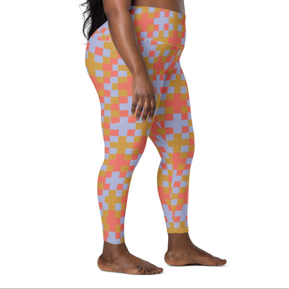 A model wearing the high-waisted Pixel Glam Sculpt Leggings, highlighting the colorful terracotta, gold, and blue pixelated grid pattern and the integrated side pocket design.