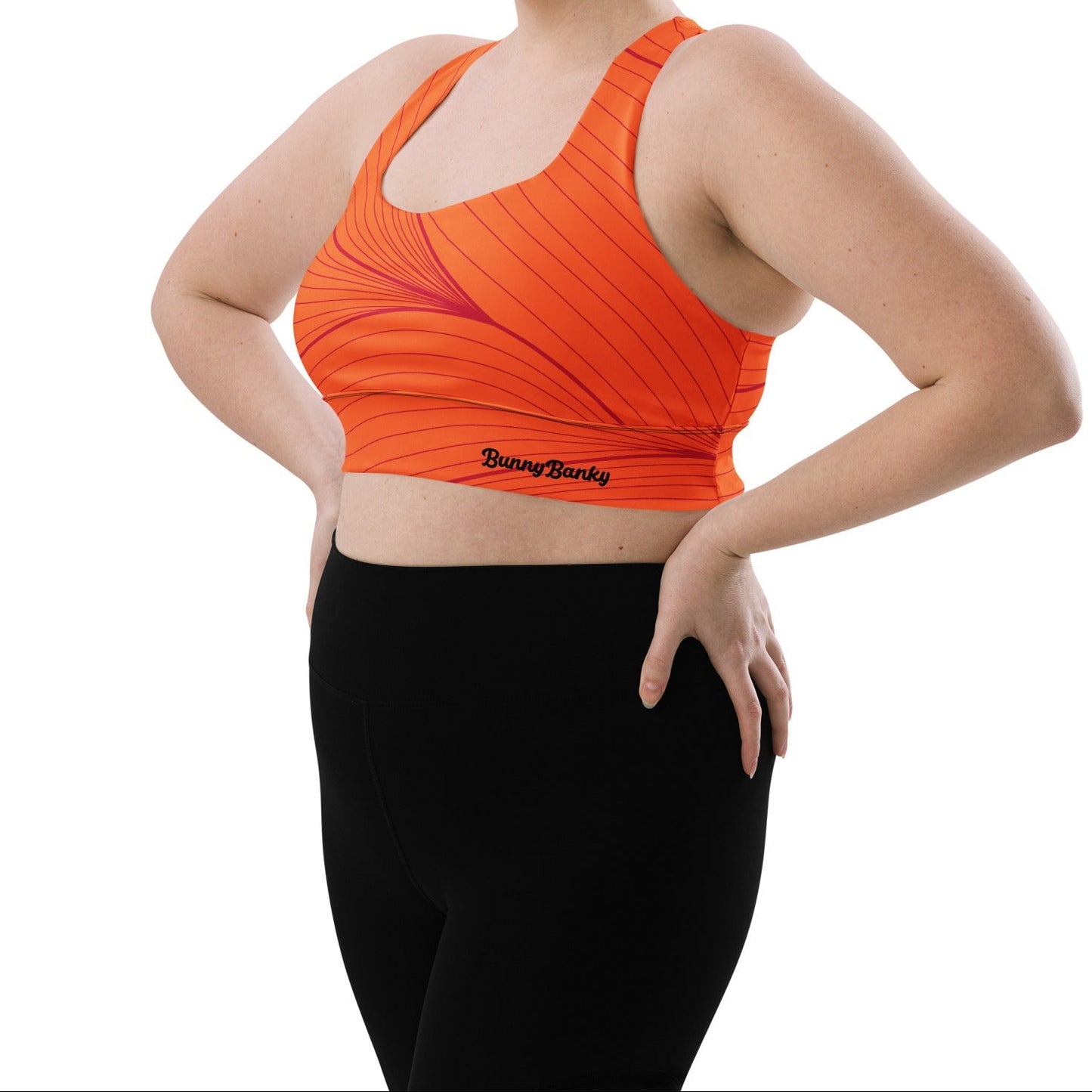 Model wearing the Rhodes Longline Performance Bra in vibrant orange geometric lines on orange background with the iconic logo and signature print at the back