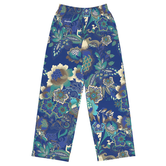 the rio flow joggers, wide-leg cut with a detailed botanical pattern in blue, green, and gold, paired with a white t-shirt and white sneakers, set against a plain white background.