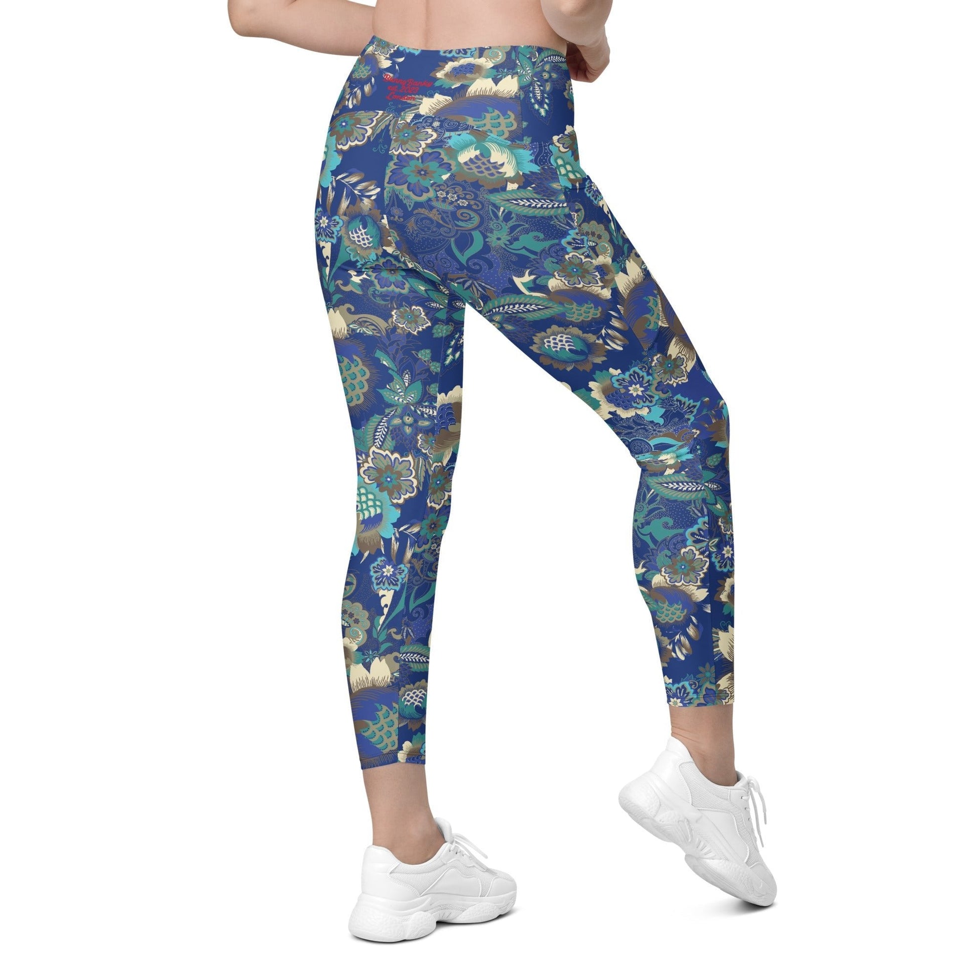 A model wearing the Rio Sculpt Leggings in the bright blue floral print, showing the flattering high-waisted fit and side pocket detail.