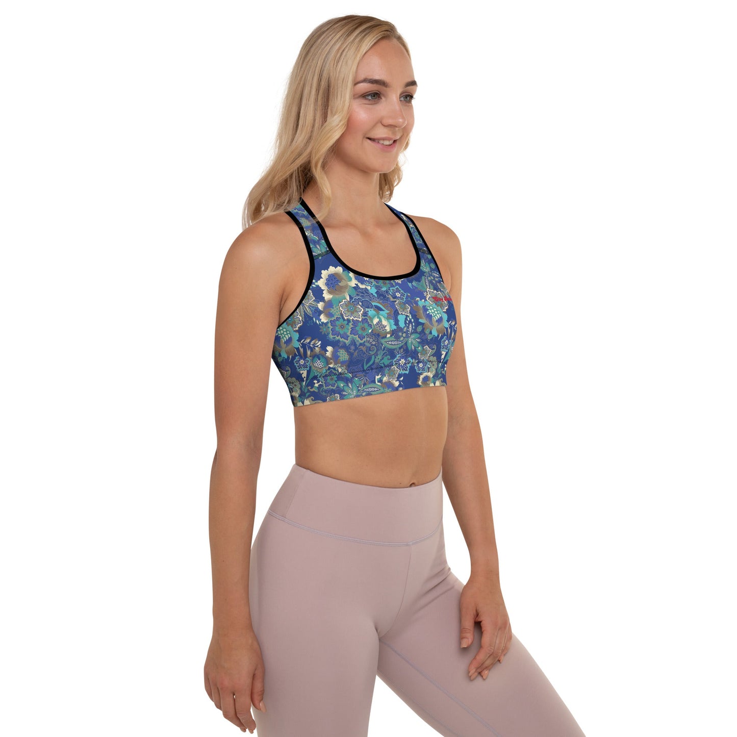 A model wearing The Rio Performance Bra, showing the supportive fit and the vibrant bright blue floral print with City Babe on the top left. Highlights the garment's construction from 74% recycled polyester.