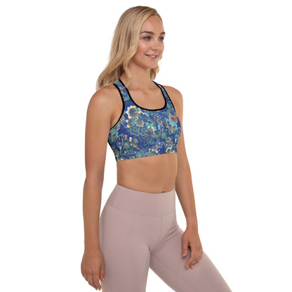 A model wearing The Rio Performance Bra, showing the supportive fit and the vibrant bright blue floral print with City Babe on the top left. Highlights the garment's construction from 74% recycled polyester.