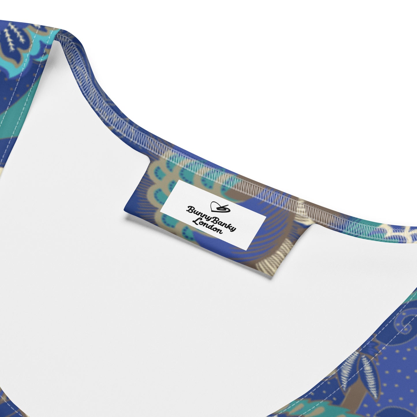 The rio performance tank. a sleeveless athletic tank top with a detailed botanical and floral pattern in navy blue, teal, and gold, paired with dark gray leggings, against a plain white background.