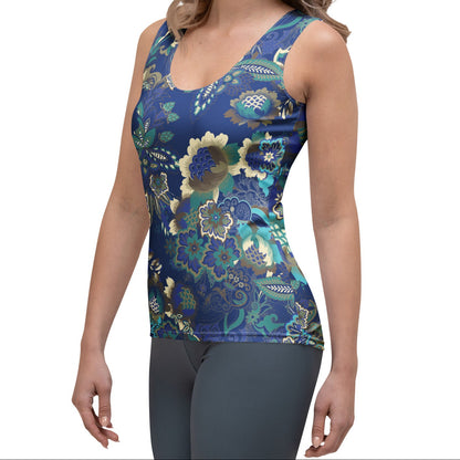 A woman modeling the rio performance tank. a sleeveless athletic tank top with a detailed botanical and floral pattern in navy blue, teal, and gold, paired with dark gray leggings, against a plain white background.