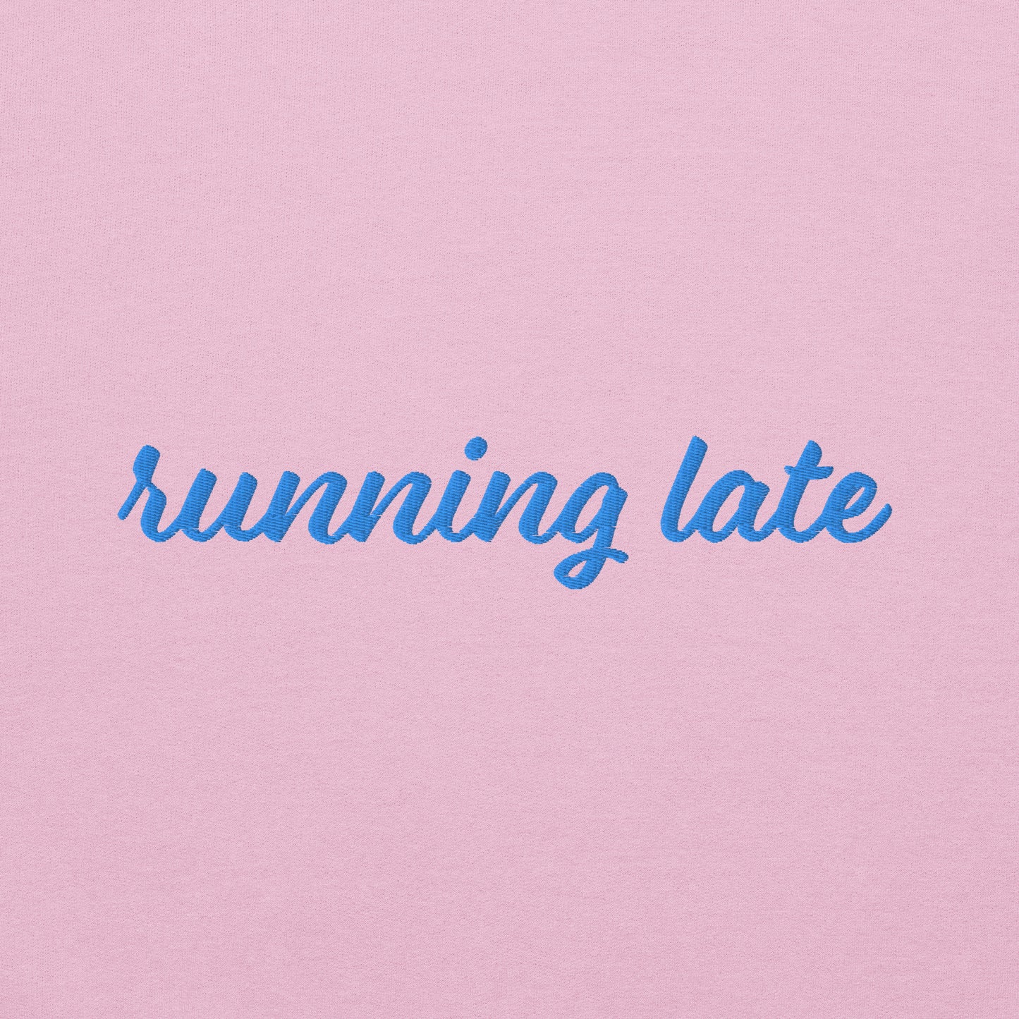 A close-up of The Running Late Sweatshirt, highlighting the "Running Late" embroidery and the iconic heart logo on the sleeve.