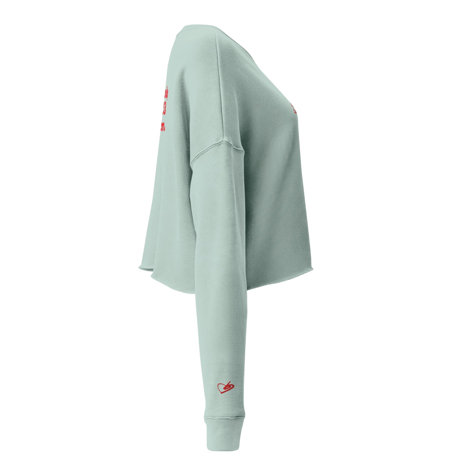 A close-up of The Sisterhood Crop Sweatshirt, highlighting the premium embroidery of the "Female Culture" motto and the soft, ring-spun cotton fabric texture, and iconic heart logo embroidered on the sleeve