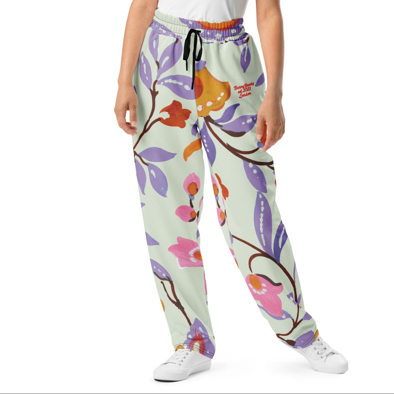 A model wearing The Sloane Square Flow Wide Joggers, showing the relaxed, wide-leg cut and the oversized pink and lilac floral print.