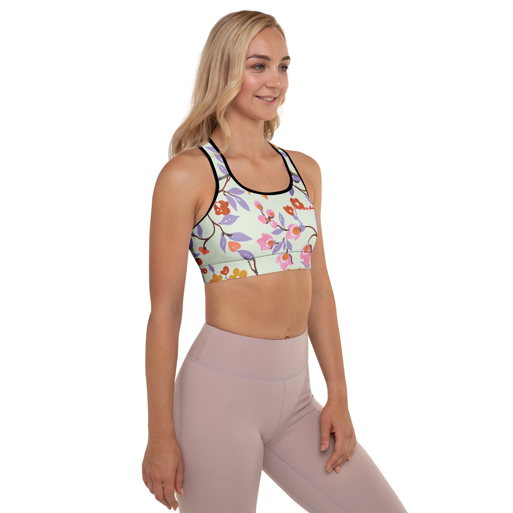A model wearing The Sloane Square Performance Bra, showing the supportive fit and the elegant pink and lilac oversized floral print.