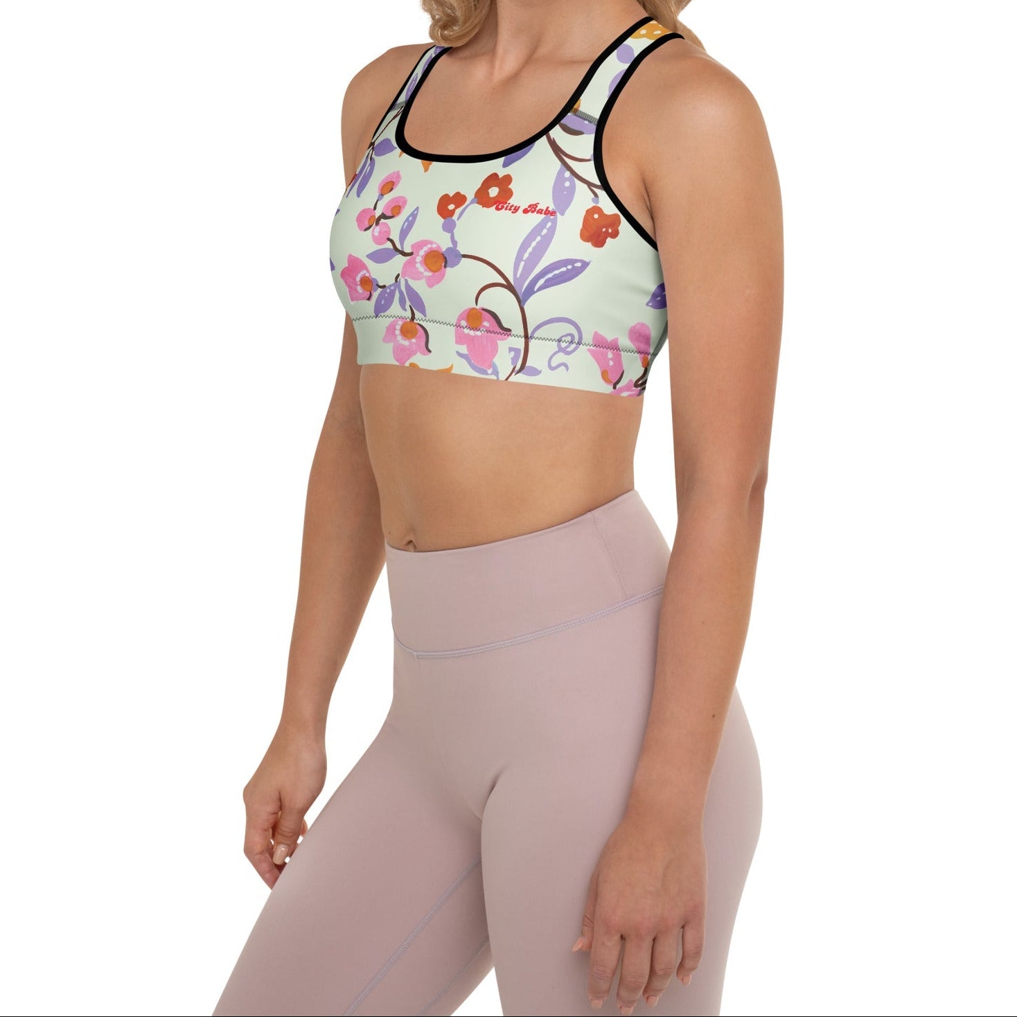 A model wearing The Sloane Square Performance Bra, showing the supportive fit and the elegant pink and lilac oversized floral print.