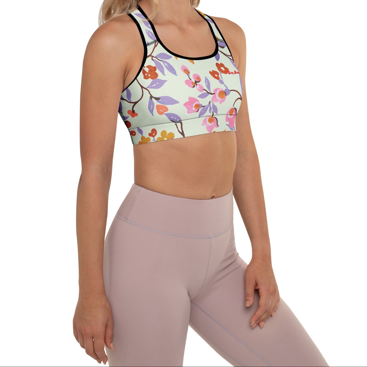 A model wearing The Sloane Square Performance Bra, showing the supportive fit and the elegant pink and lilac oversized floral print.