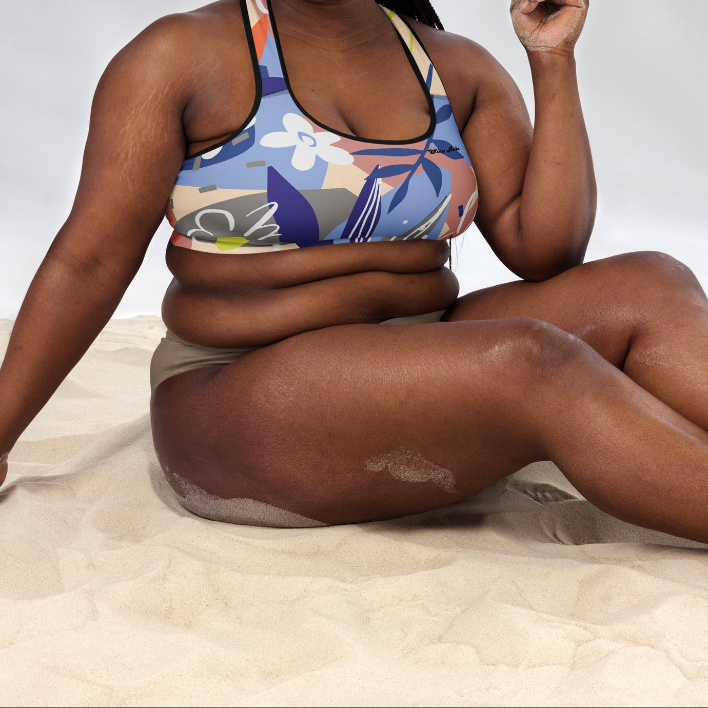 A model wearing the surrey performance bra with the print city babe on a floral print with lilac and beige hues