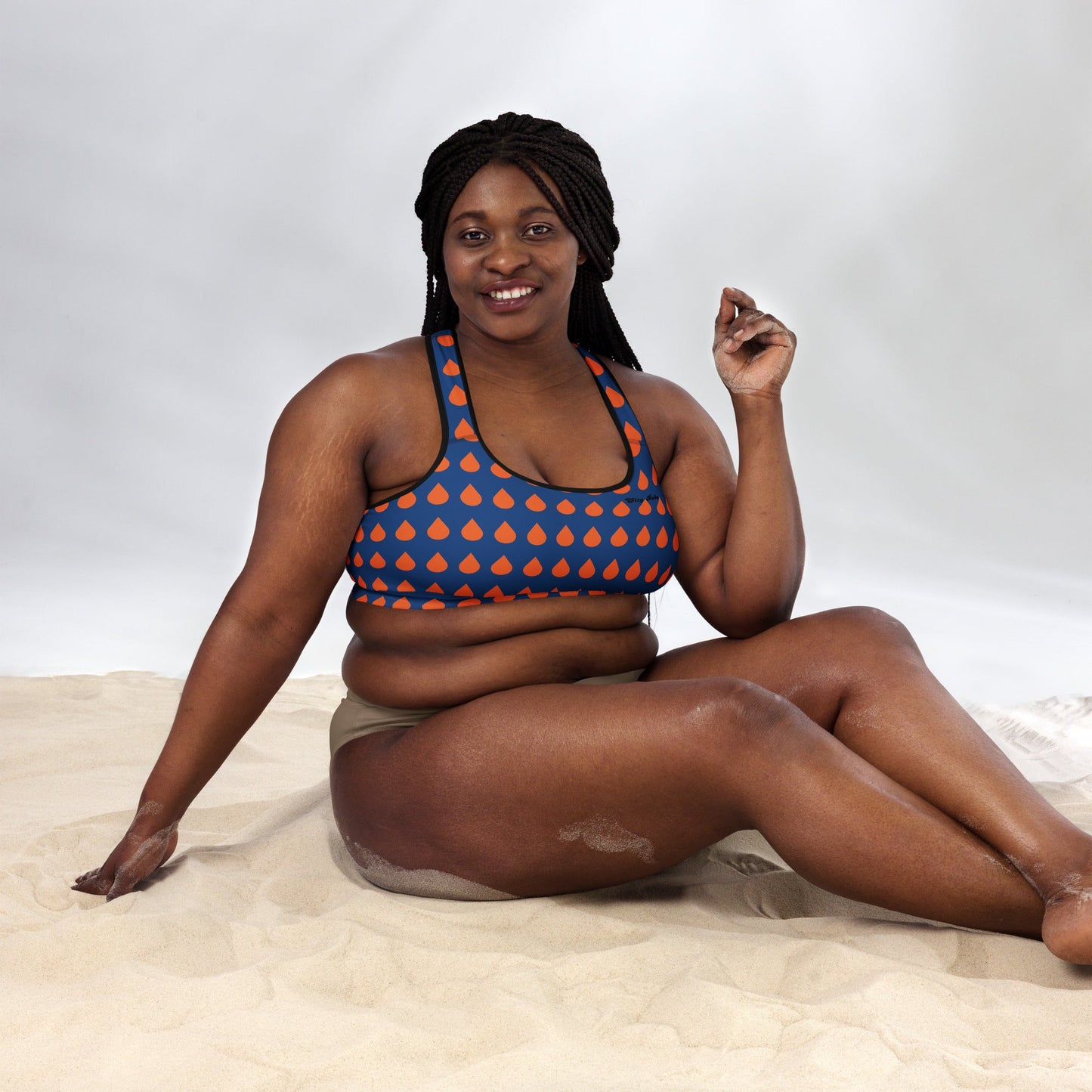 A model wearing The Thames Performance Bra, showing the supportive fit and the sophisticated orange drops print on the deep navy blue background. Highlights the garment's construction and the City Babe text printed in black on the top left 