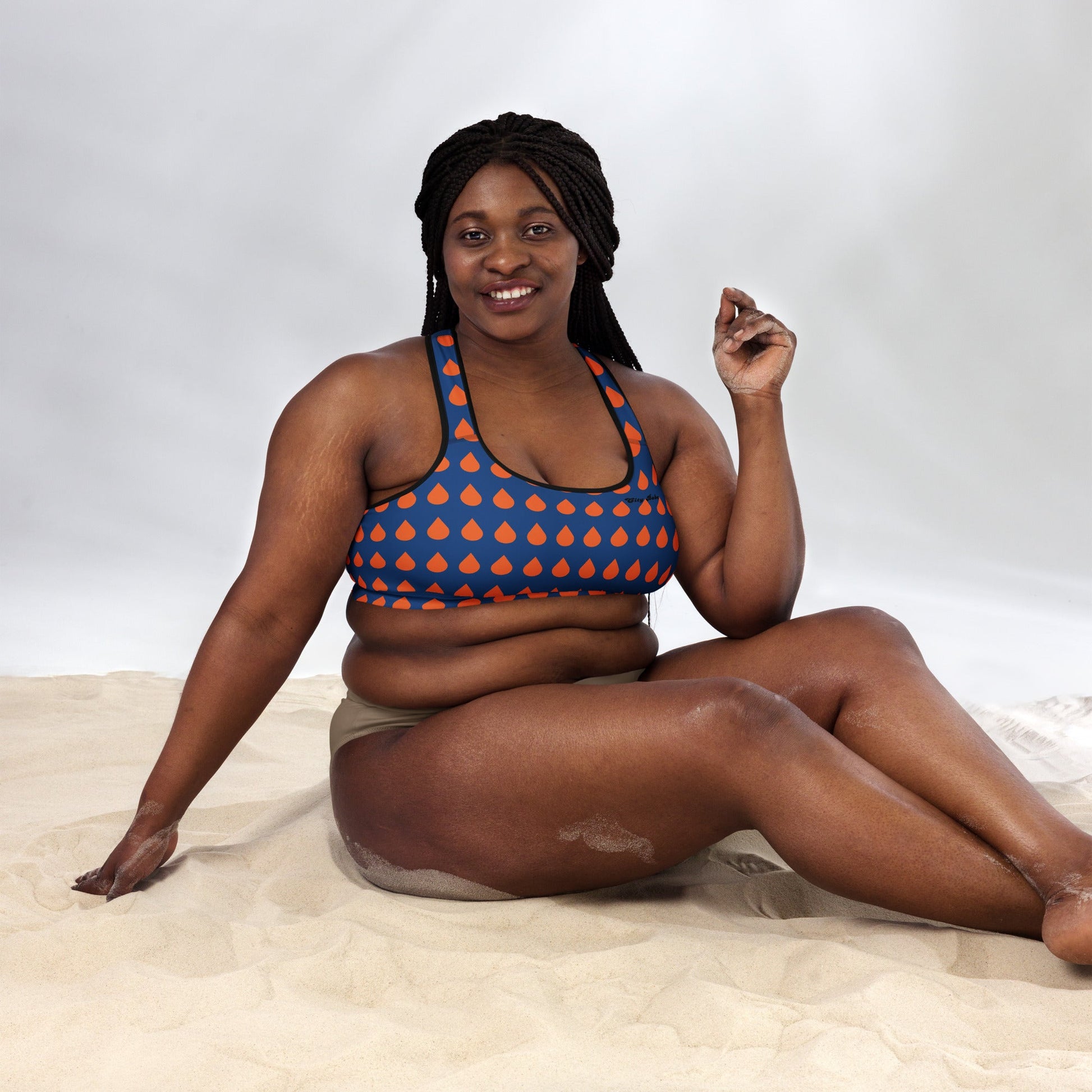 A model wearing The Thames Performance Bra, showing the supportive fit and the sophisticated orange drops print on the deep navy blue background. Highlights the garment's construction and the City Babe text printed in black on the top left 