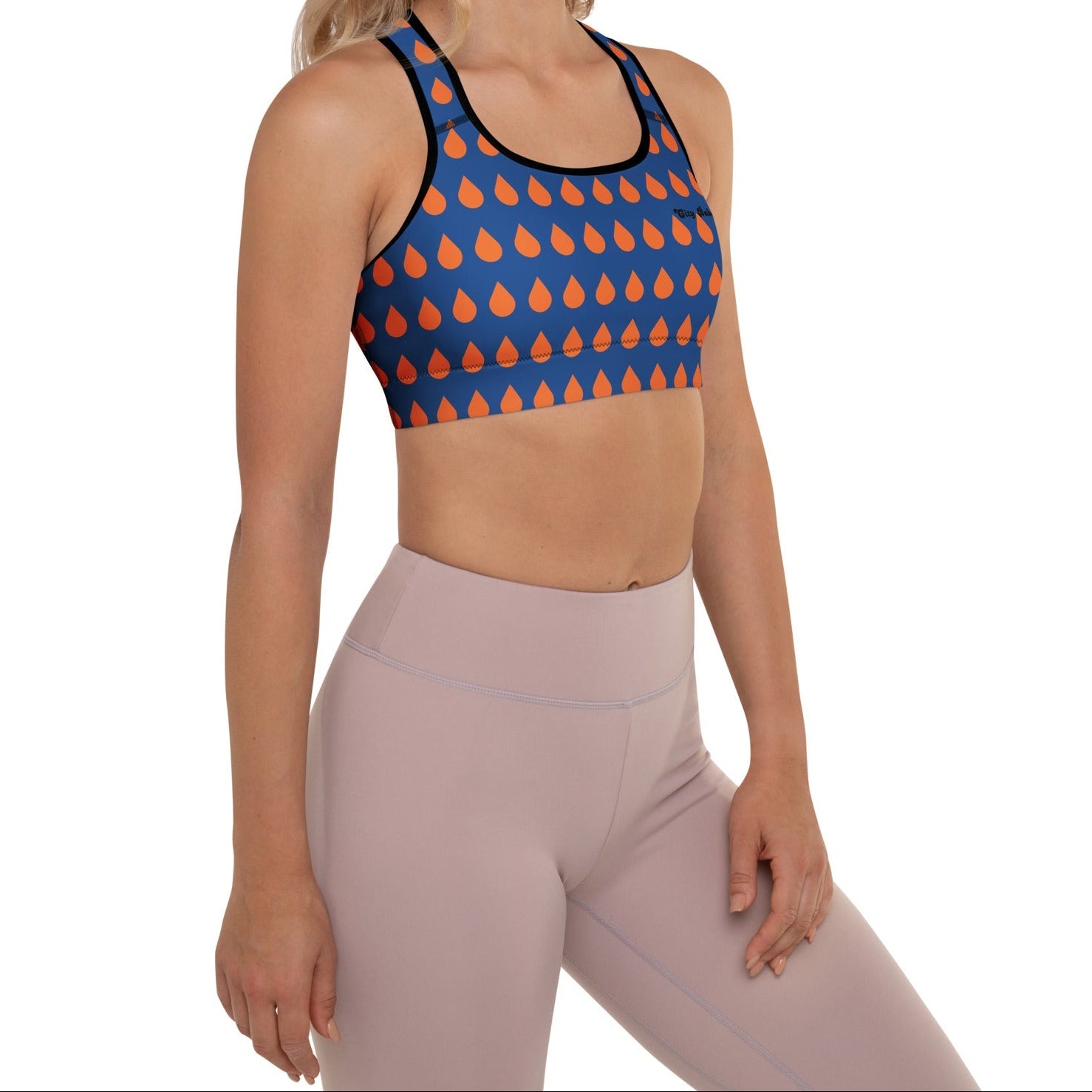 A model wearing The Thames Performance Bra, showing the supportive fit and the sophisticated orange drops print on the deep navy blue background. Highlights the garment's construction and the City Babe text printed in black on the top left 