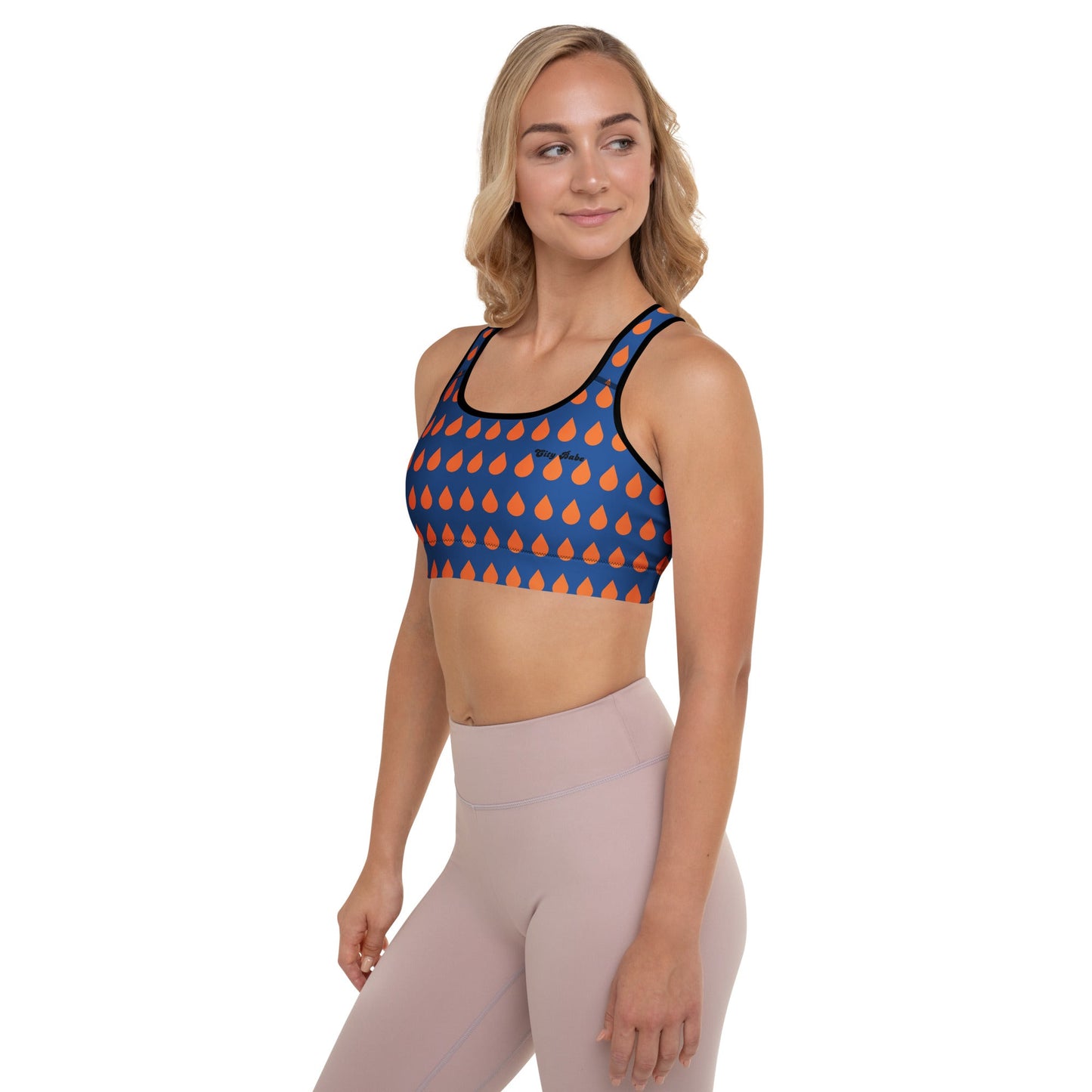 A model wearing The Thames Performance Bra, showing the supportive fit and the sophisticated orange drops print on the deep navy blue background. Highlights the garment's construction and the City Babe text printed in black on the top left 