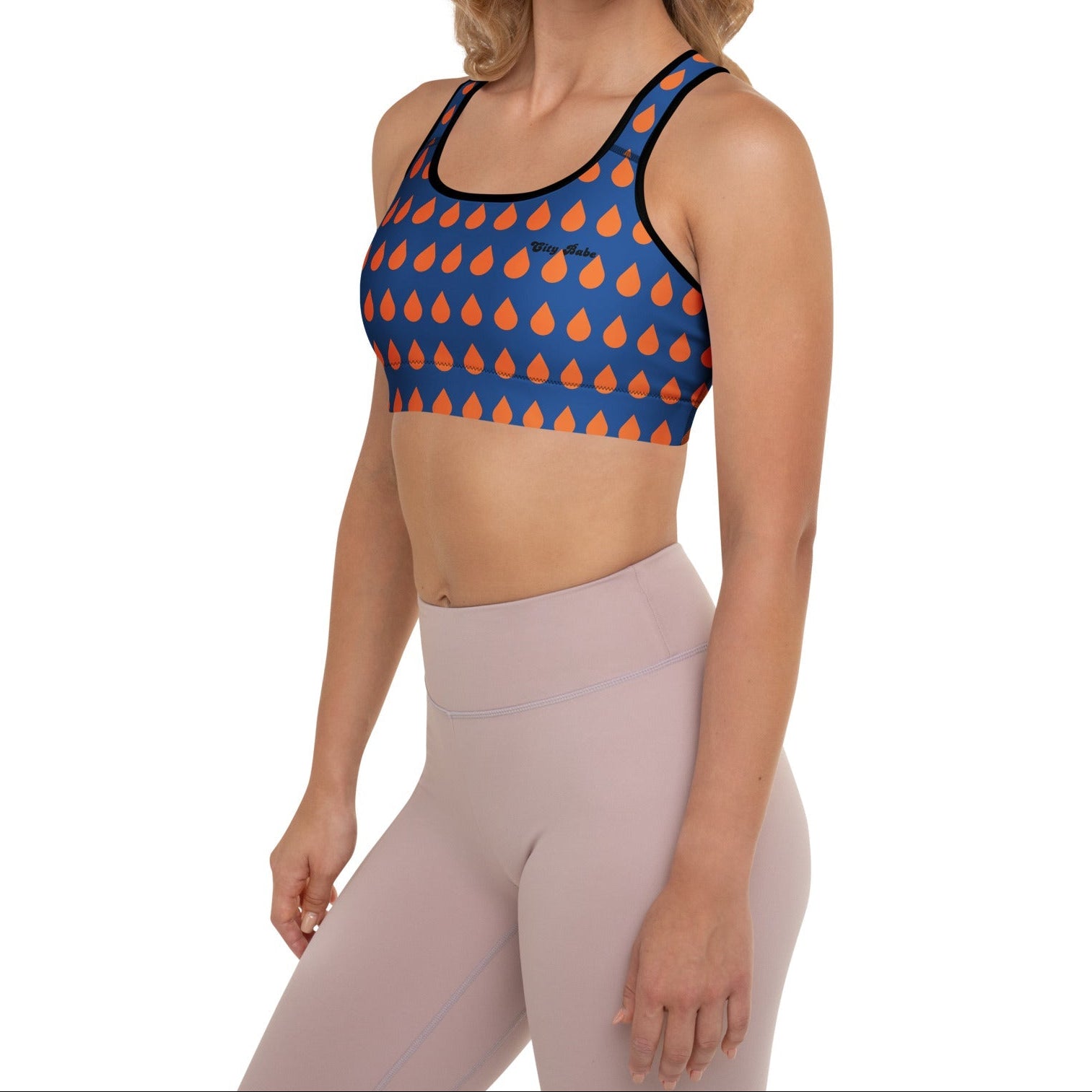 A model wearing The Thames Performance Bra, showing the supportive fit and the sophisticated orange drops print on the deep navy blue background. Highlights the garment's construction and the City Babe text printed in black on the top left 