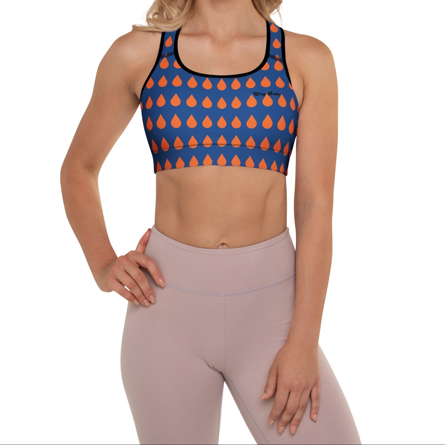 A model wearing The Thames Performance Bra, showing the supportive fit and the sophisticated orange drops print on the deep navy blue background. Highlights the garment's construction and the City Babe text printed in black on the top left 