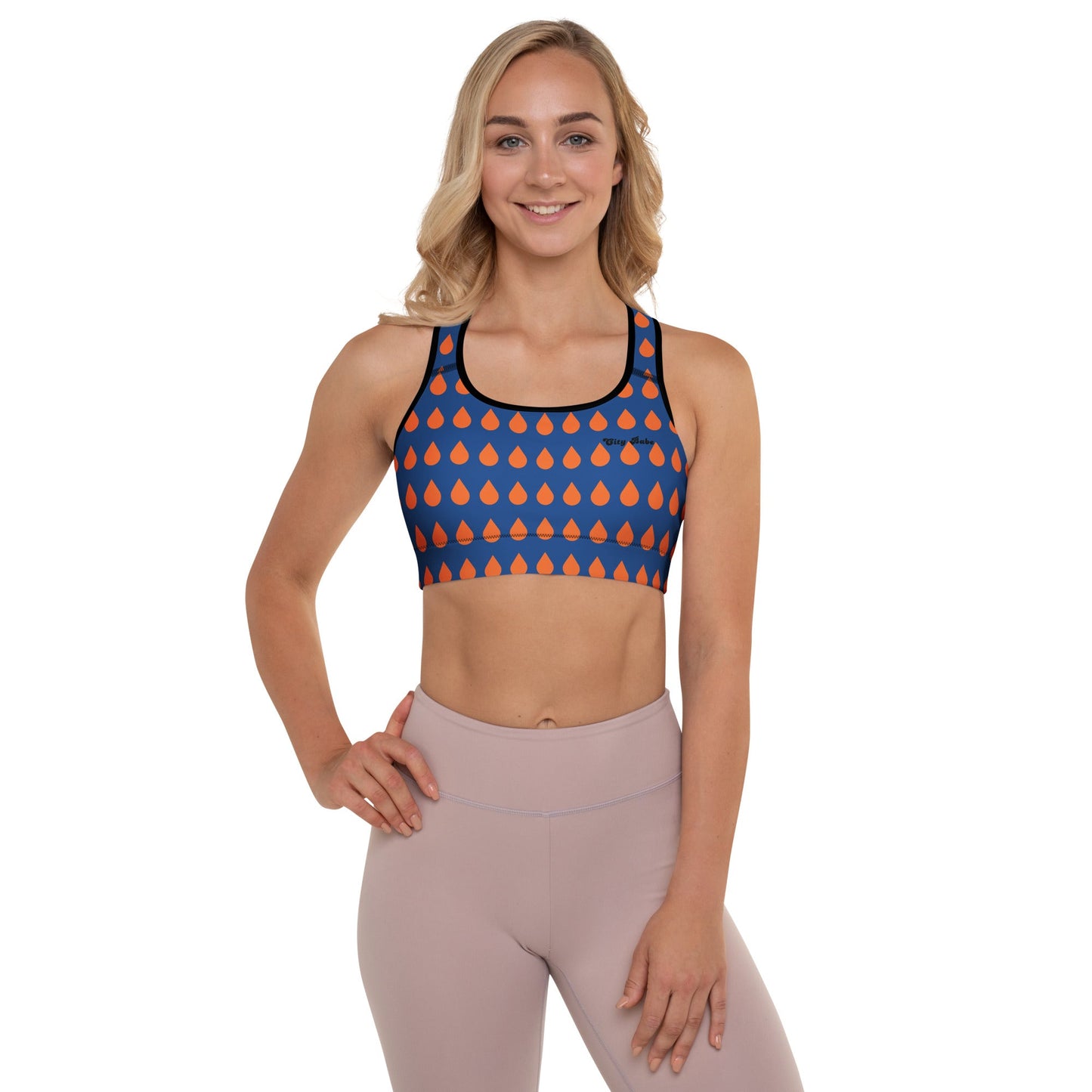 A model wearing The Thames Performance Bra, showing the supportive fit and the sophisticated orange drops print on the deep navy blue background. Highlights the garment's construction and the City Babe text printed in black on the top left 