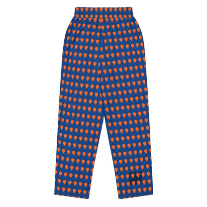 A close up of The Thames Flow Joggers, showing the wide-leg, relaxed silhouette and the orange drop print on the deep navy blue background.