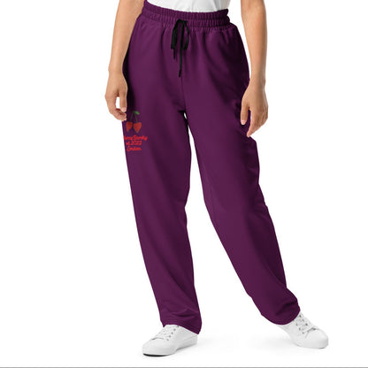A model wearing The Tokyo Purple Flow  Joggers, showing the relaxed, wide-leg cut and the playful Pop Cherry print on the dark purple fabric.