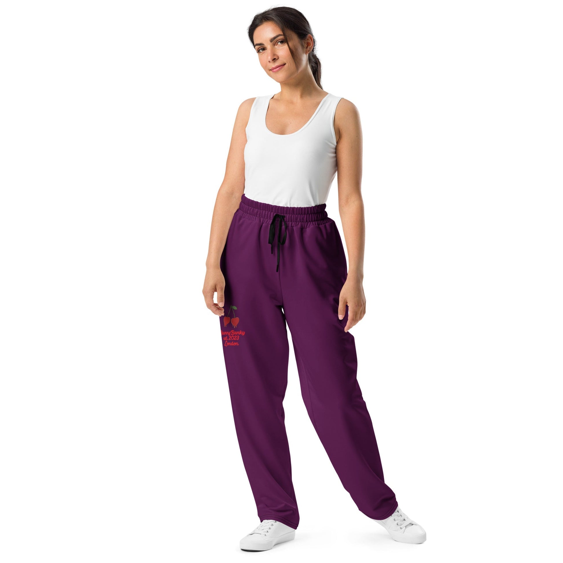 A model wearing The Tokyo Purple Flow Wide Joggers, showing the relaxed, wide-leg cut and the playful Pop Cherry print on the dark purple fabric.