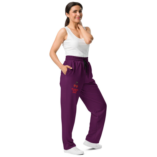 A model wearing The Tokyo Purple Flow Wide Joggers, showing the relaxed, wide-leg cut and the playful Pop Cherry print on the dark purple fabric.