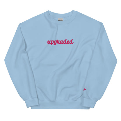 A close-up of The Upgrade Sweatshirt, highlighting the bold "Upgraded" text embroidered in fuschia on the chest, the soft air-jet spun fabric, and the detailed heritage logo print on the back.